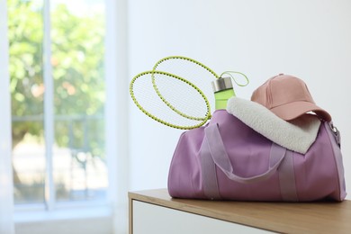 Photo of Stylish bag with sports equipment on wooden table at home. Space for text