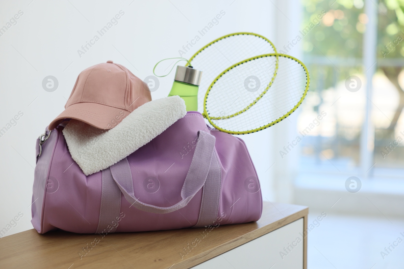 Photo of Stylish bag with sports equipment on wooden table at home