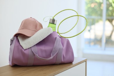 Photo of Stylish bag with sports equipment on wooden table at home
