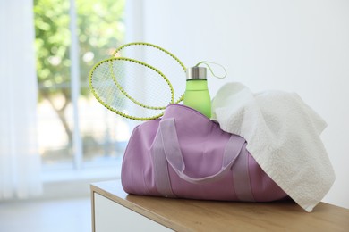 Photo of Stylish bag with sports equipment on wooden table at home