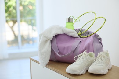 Photo of Stylish bag with sports equipment on wooden table at home. Space for text