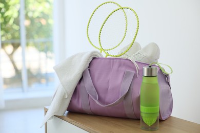 Photo of Stylish bag with sports equipment on wooden table at home. Space for text