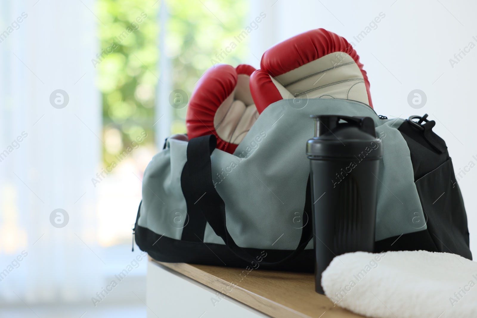 Photo of Stylish bag with sports equipment on wooden table at home. Space for text