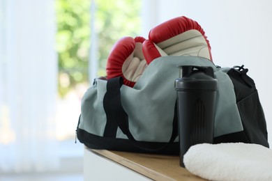 Photo of Stylish bag with sports equipment on wooden table at home. Space for text