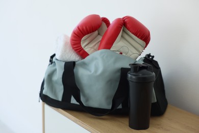 Photo of Stylish bag with sports equipment on wooden table at home