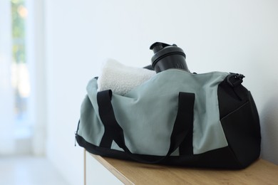 Photo of Stylish bag with sports equipment on wooden table at home. Space for text