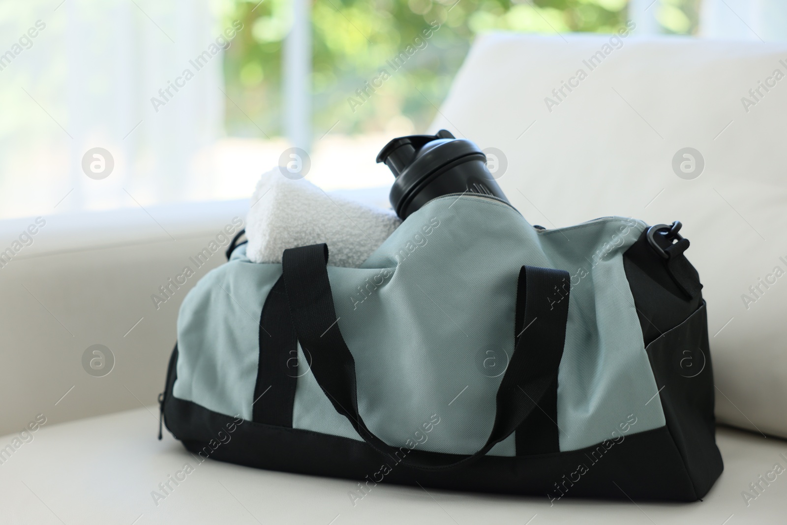 Photo of Stylish bag with sports equipment on sofa at home