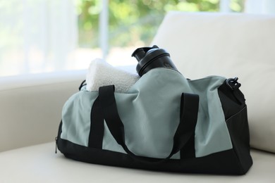 Photo of Stylish bag with sports equipment on sofa at home