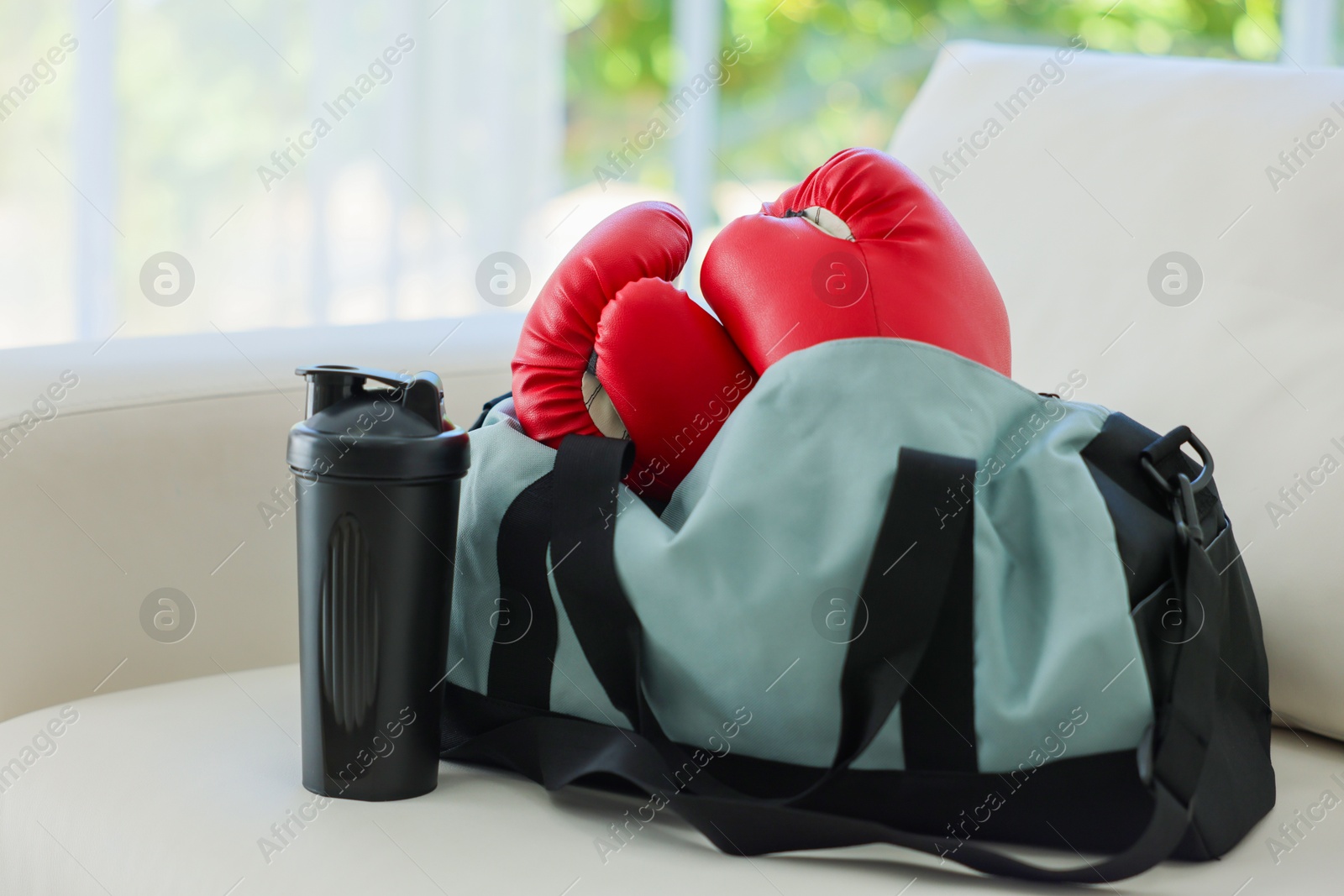 Photo of Stylish bag with sports equipment on sofa at home