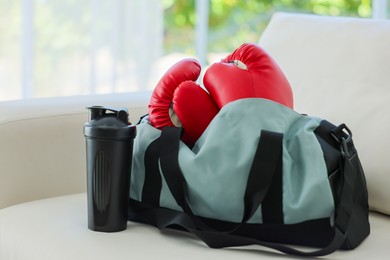 Photo of Stylish bag with sports equipment on sofa at home