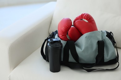 Photo of Stylish bag with sports equipment on sofa at home