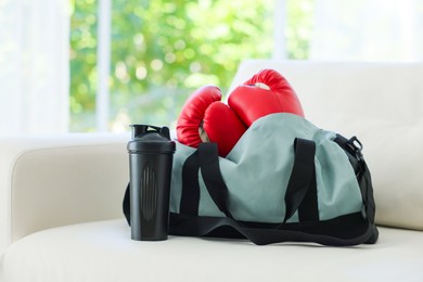 Photo of Stylish bag with sports equipment on sofa at home
