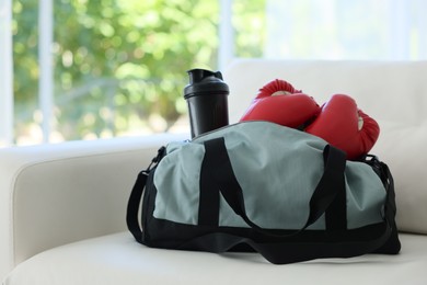 Photo of Stylish bag with sports equipment on sofa at home. Space for text