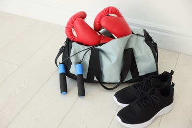 Photo of Stylish bag with sports equipment on floor indoors