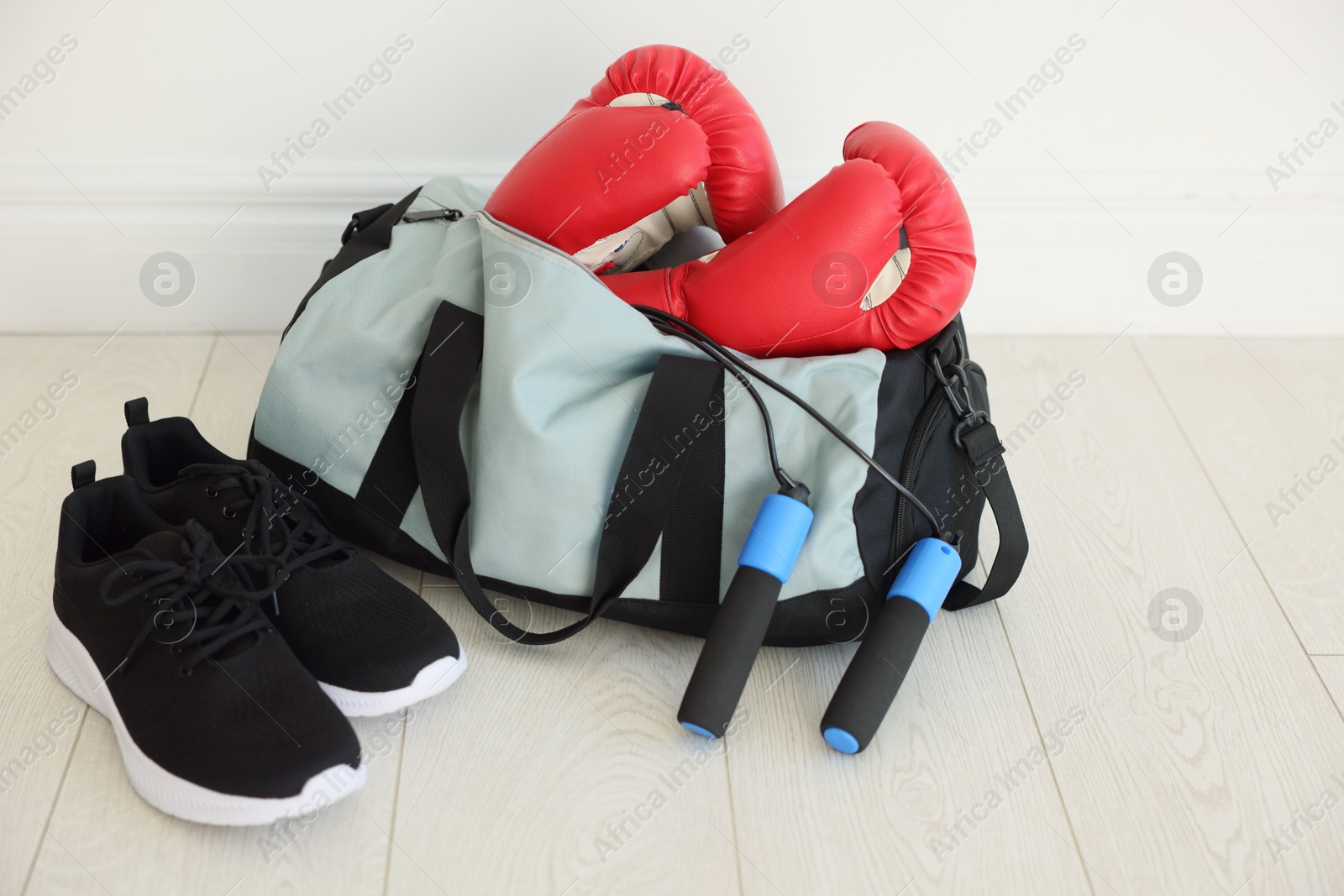 Photo of Stylish bag with sports equipment on floor indoors