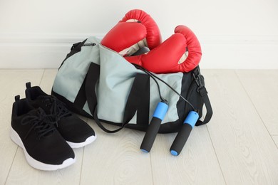 Photo of Stylish bag with sports equipment on floor indoors