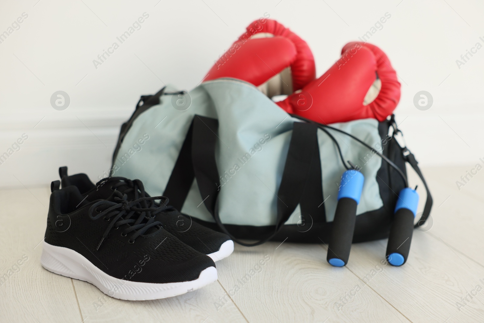 Photo of Stylish bag with sports equipment on floor indoors