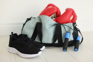 Photo of Stylish bag with sports equipment on floor indoors