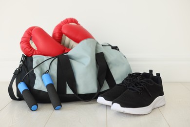 Photo of Stylish bag with sports equipment on floor indoors