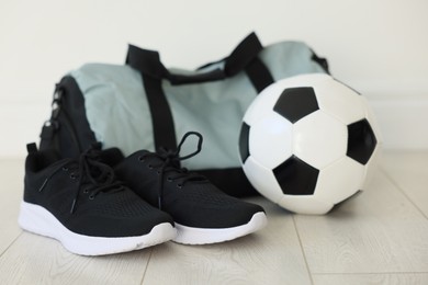 Photo of Stylish bag with sports equipment on floor indoors