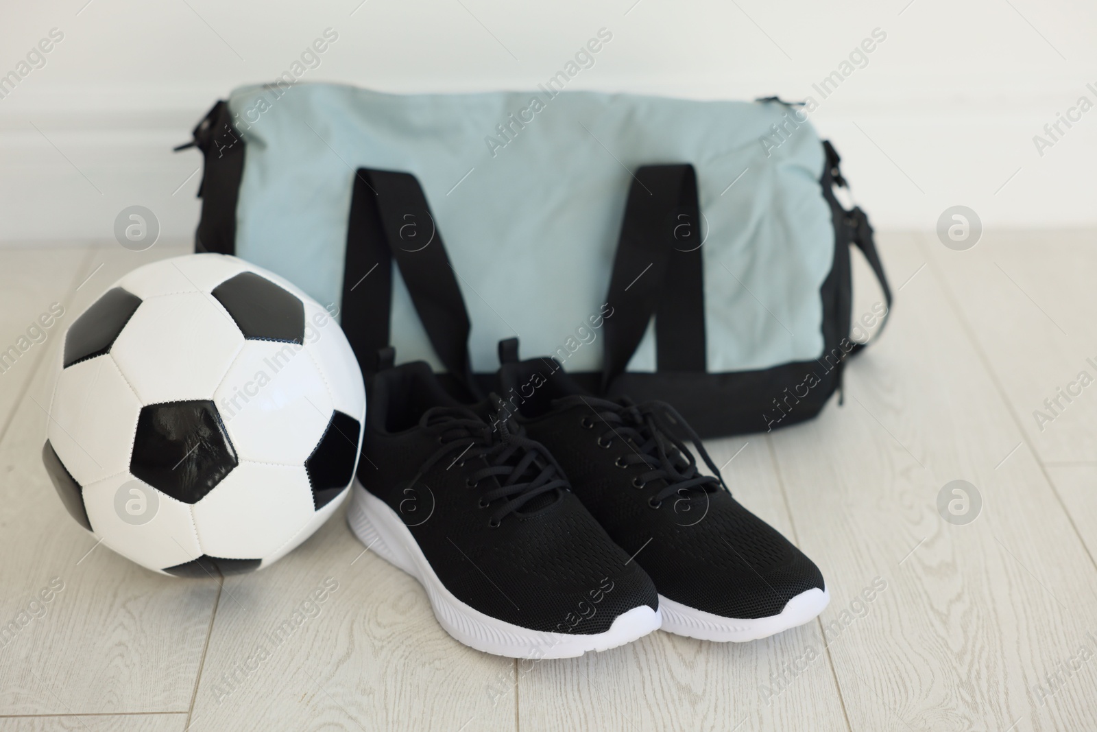 Photo of Stylish bag with sports equipment on floor indoors