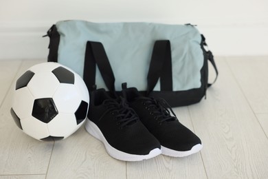 Photo of Stylish bag with sports equipment on floor indoors