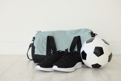 Photo of Stylish bag with sports equipment on floor indoors