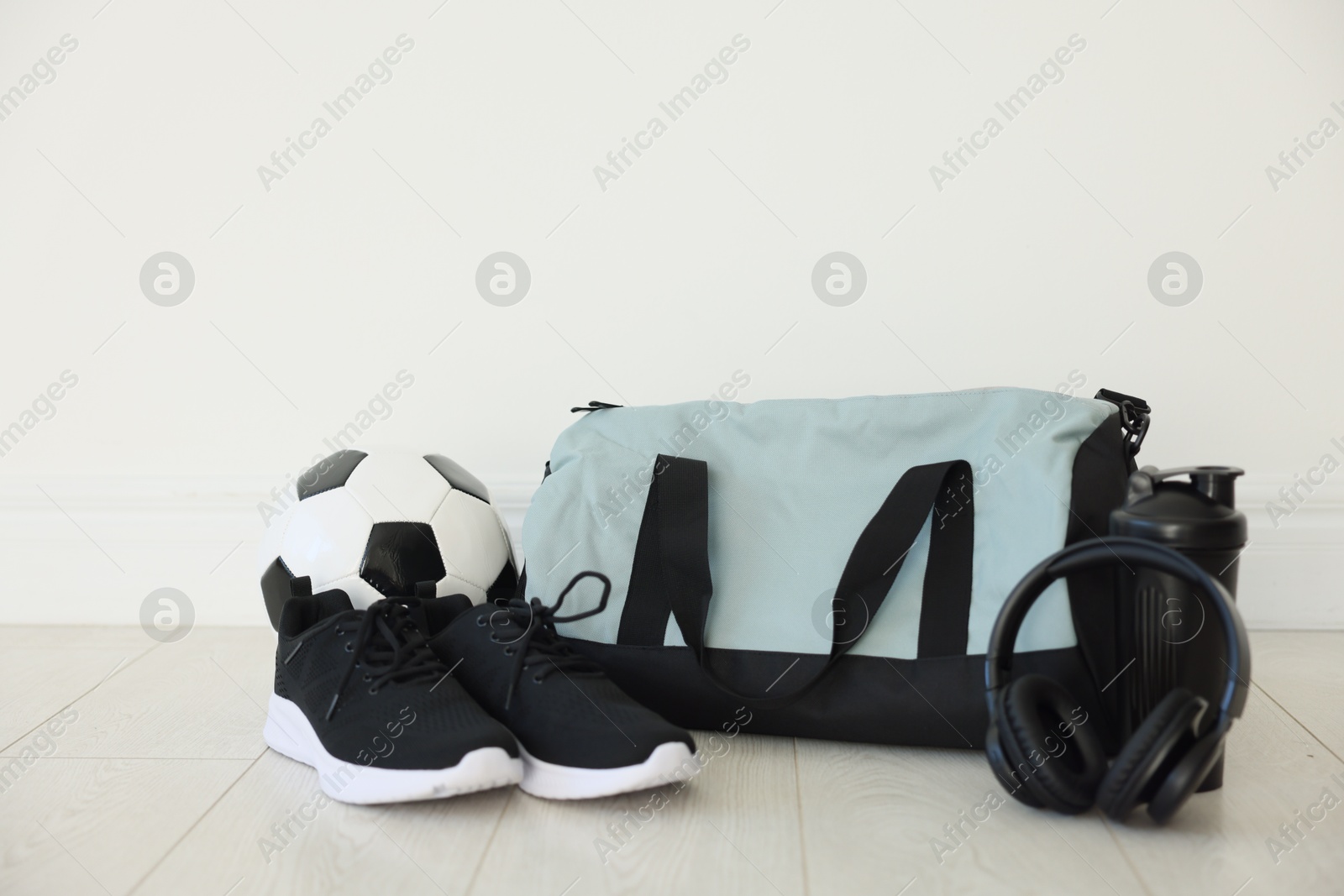 Photo of Stylish bag with sports equipment on floor indoors