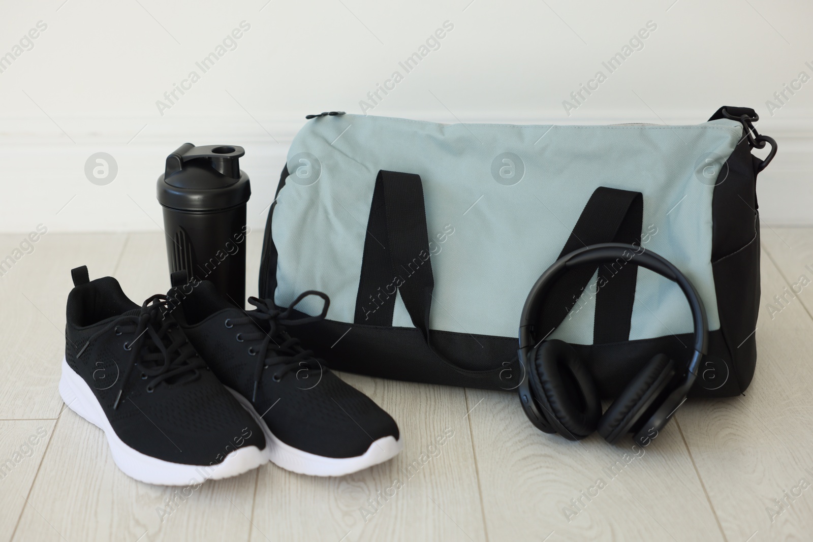 Photo of Stylish bag with sports equipment on floor indoors