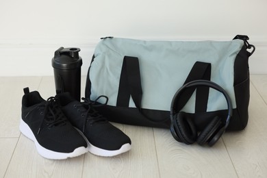 Photo of Stylish bag with sports equipment on floor indoors
