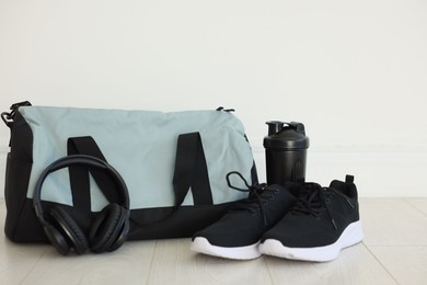 Photo of Stylish bag with sports equipment on floor indoors