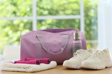 Photo of Stylish bag with sports equipment on wooden table at home