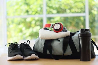 Photo of Stylish bag with sports equipment on wooden table at home