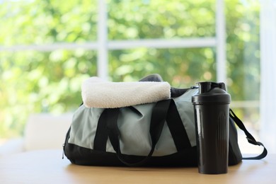 Photo of Stylish bag with sports equipment on wooden table at home