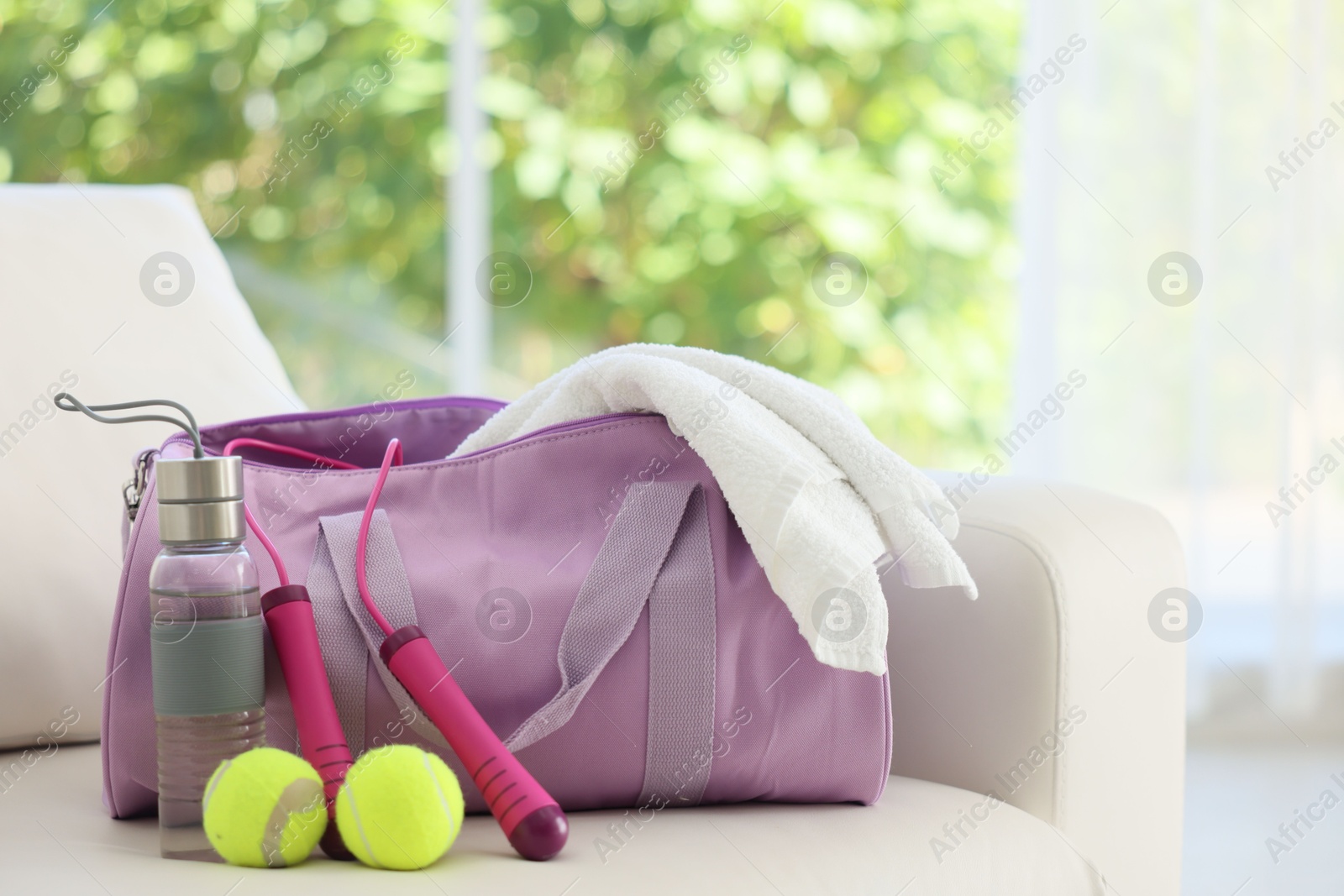 Photo of Stylish bag with sports equipment on sofa at home