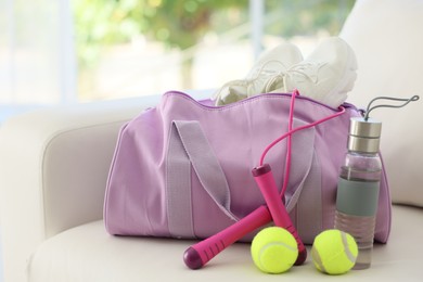 Photo of Stylish bag with sports equipment on sofa at home