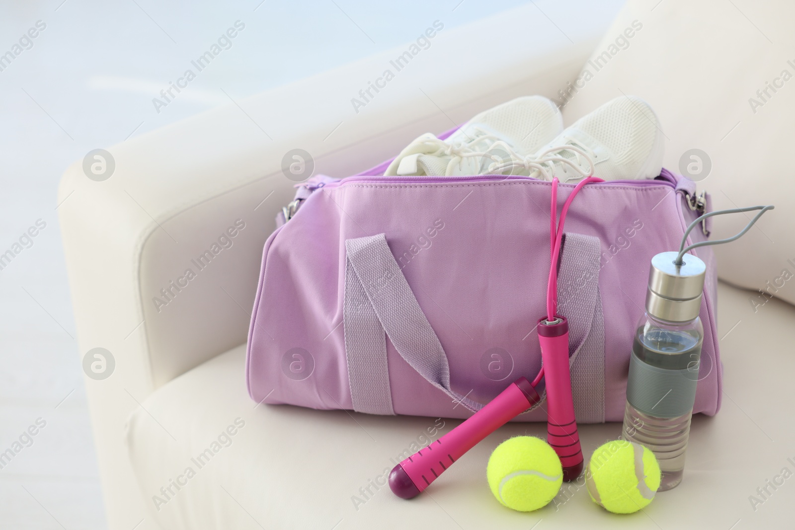 Photo of Stylish bag with sports equipment on sofa at home