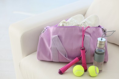Photo of Stylish bag with sports equipment on sofa at home