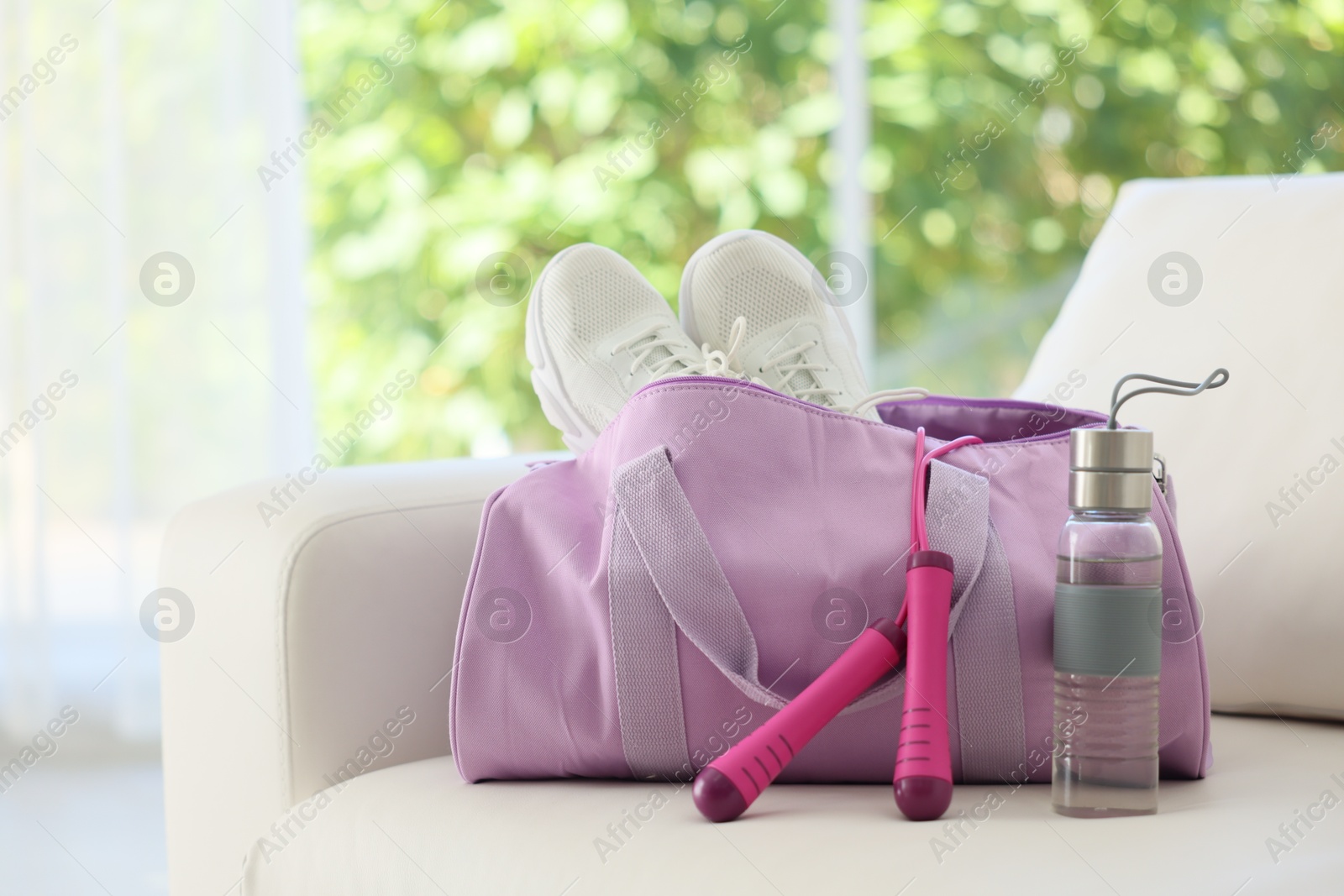 Photo of Stylish bag with sports equipment on sofa at home