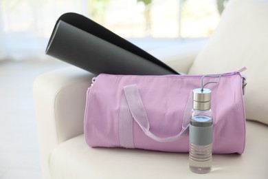 Photo of Stylish bag with sports equipment on sofa at home