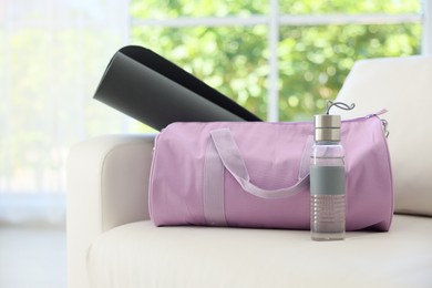 Photo of Stylish bag with sports equipment on sofa at home