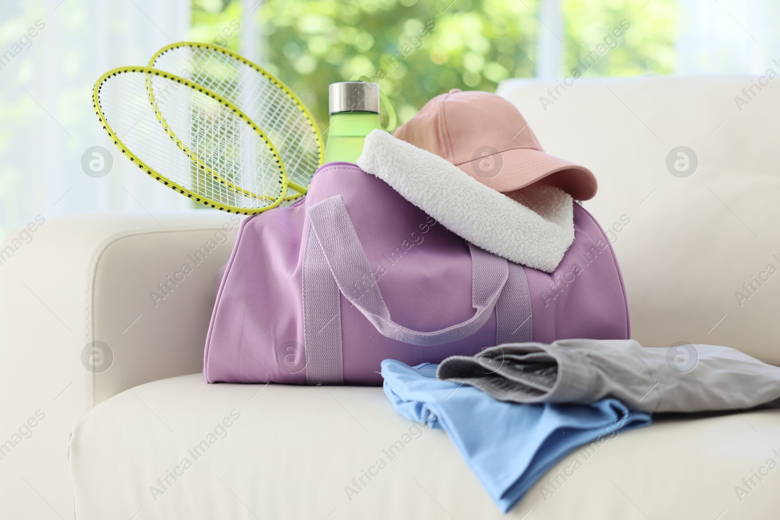 Photo of Stylish bag with sports equipment on sofa at home