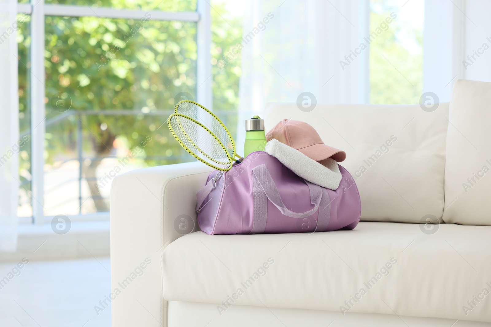 Photo of Stylish bag with sports equipment on sofa at home