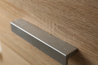 Photo of Handle of dresser covered with dust indoors, closeup