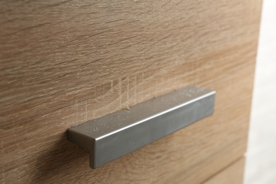 Photo of Handle of dresser covered with dust indoors, closeup