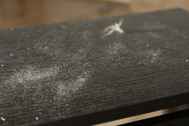 Photo of Black wooden table covered with dust indoors, closeup