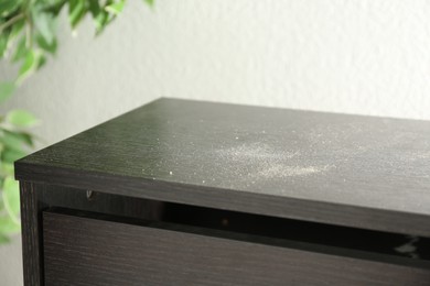 Photo of Black wooden cabinet covered with dust indoors, closeup