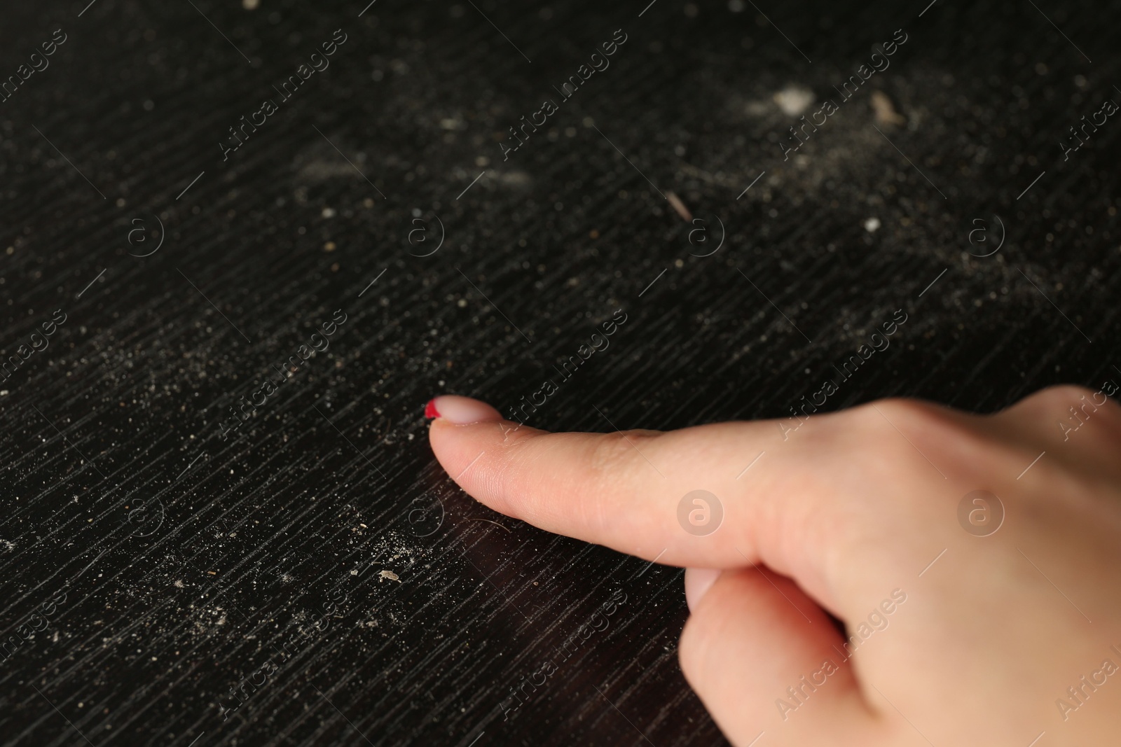 Photo of Woman swiping dust from black wooden table, closeup