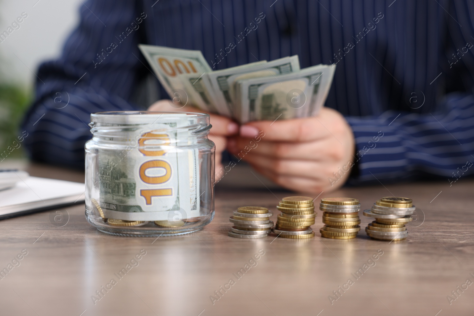 Photo of Woman counting dollars at wooden table indoors, closeup