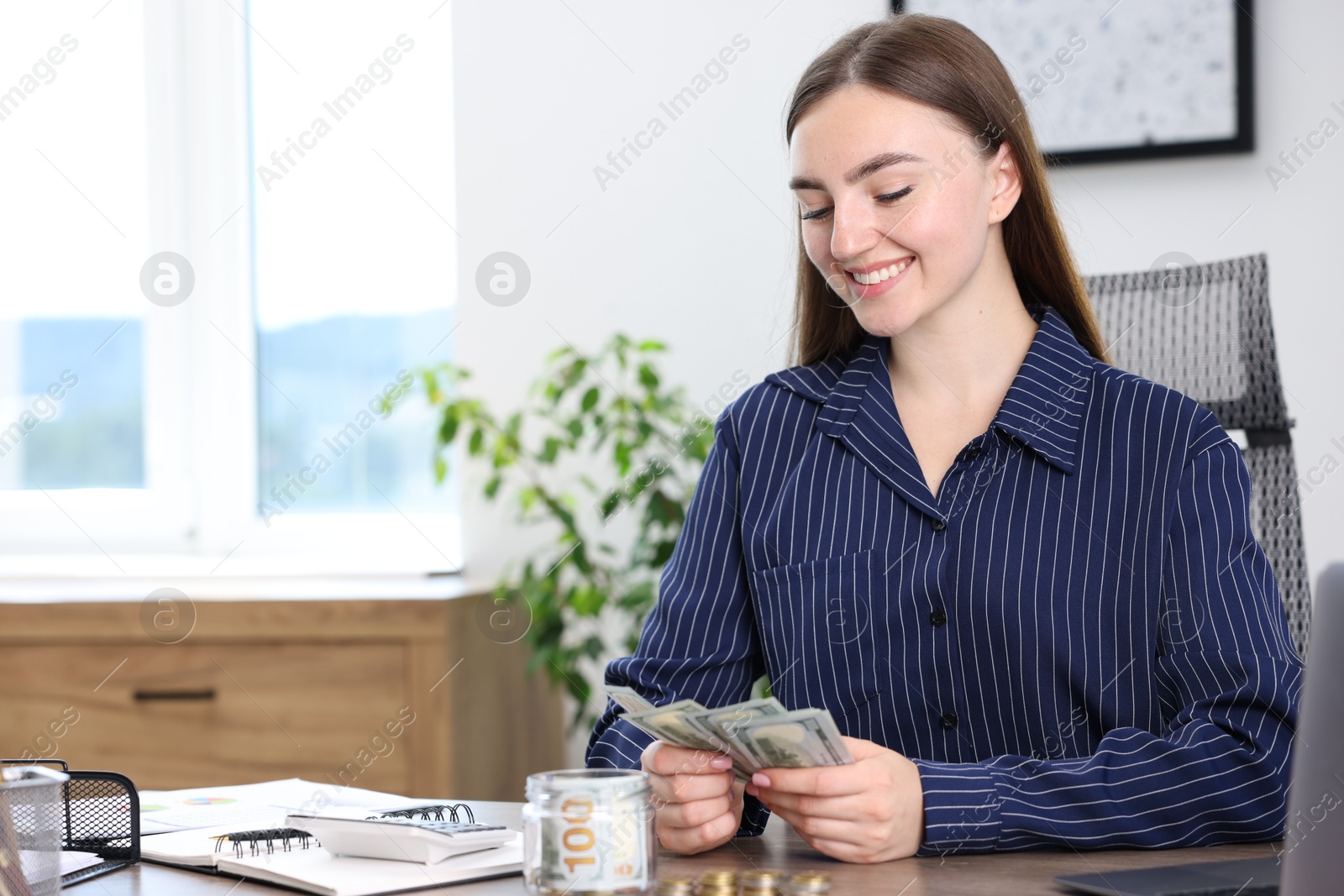 Photo of Woman counting dollars at wooden table indoors, space for text